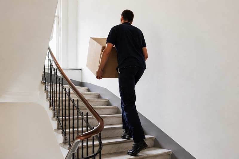 Déménageur montant un escalier avec un carton dans une résidence étudiante